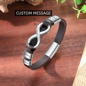 May include: A brown leather bracelet with a silver infinity symbol and magnetic clasp. The infinity symbol has the words "Always and forever" engraved on it. The bracelet has three small silver bands with names engraved on them. The text "CUSTOM MESSAGE" is above the bracelet.
