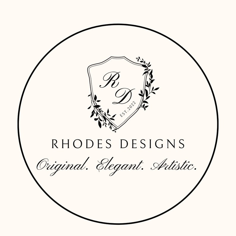 May include: Black and white logo design with a shield featuring the letters "R" and "D" surrounded by a wreath of leaves. The text "Rhodes Designs" is below the shield, and the text "Original. Elegant. Artistic." is below that.