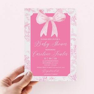 May include: Pink baby shower invitation with a white floral pattern and a large pink bow. The invitation includes the text "Please join us for a Baby Shower honoring Caroline Fowler 11 | 30 | 23 123 Anywhere Street Mulberry, GA 30234 12:00 pm - 2:00 pm Kindly RSVP to Macy at (404) 343-1243 Registered at AMAZON & TARGET"
