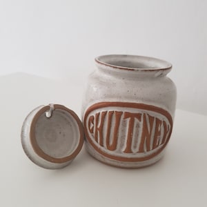May include: White ceramic jar with a brown lid and the word "CHUTNEY" written in brown on the front.
