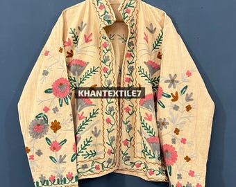 Può includere: Giacca beige ricamata con motivi floreali rosa, verdi e marroni. La giacca presenta maniche lunghe e un design aperto sul davanti. Il testo "KHANTEXTILE7" è visibile sul davanti.