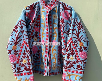 May include: A light blue jacket with intricate floral embroidery in shades of red, pink, and yellow. The jacket features a high collar and is adorned with the text "KHANTEXTILE7". The embroidery creates a detailed and colorful pattern across the jacket's surface.