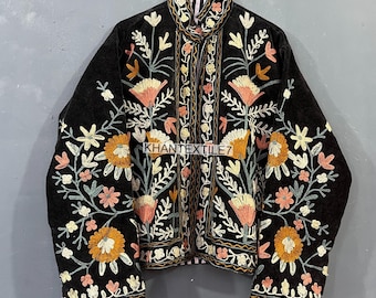May include: Black jacket with intricate floral embroidery in shades of orange, pink, and cream. The jacket features a high collar and is adorned with the text "KHANTEXTILE7". The embroidery is detailed and covers the front and sleeves.