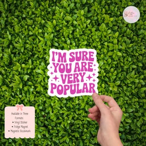 以下が含まれることがあります： ピンク色の「I'M SURE YOU ARE VERY POPULAR」という文字が書かれた白いステッカー。緑の葉の背景に配置されています。ビニールステッカー、冷蔵庫用マグネット、またはマグネットブックマークとして利用できます。