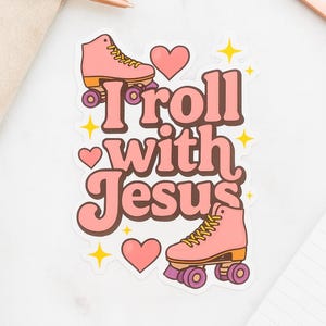 May include: A sticker with the phrase "Roll with Jesus" in pink bubble letters, featuring two pink roller skates and heart and star accents. The skates have yellow laces and purple wheels.