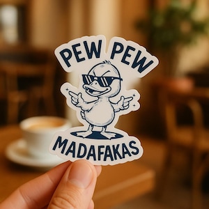 May include: A white sticker featuring a cartoon duck wearing sunglasses and pointing its wings. The sticker has the words "PEW PEW" above the duck and "MADAFKAS" below it, all in a dark blue color.