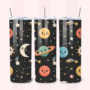 Peut inclure: Trois gobelets cylindriques avec couvercles et pailles, présentant un fond noir avec un motif répétitif de corps célestes souriants, incluant un soleil jaune, un croissant de lune, une planète à anneaux, des étoiles, des constellations et des comètes colorées.