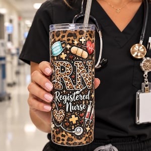 May include: A cylindrical stainless steel tumbler with a clear lid and metal straw, featuring a leopard print background, medical icons including a face mask, bandage, heart, and syringes, and the text "RN Registered Nurse" in bold lettering.