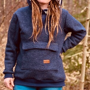 May include: A dark blue hooded sweatshirt with a large front pocket and a brown leather patch with the word "Handmade" on it.