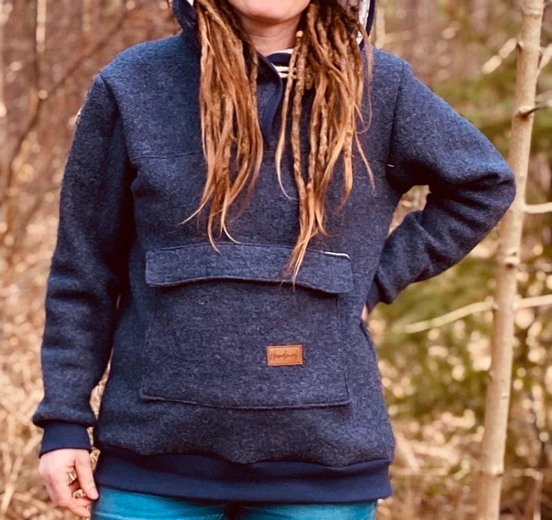 May include: A dark blue hooded sweatshirt with a large front pocket and a brown leather patch with the word "Handmade" on it.