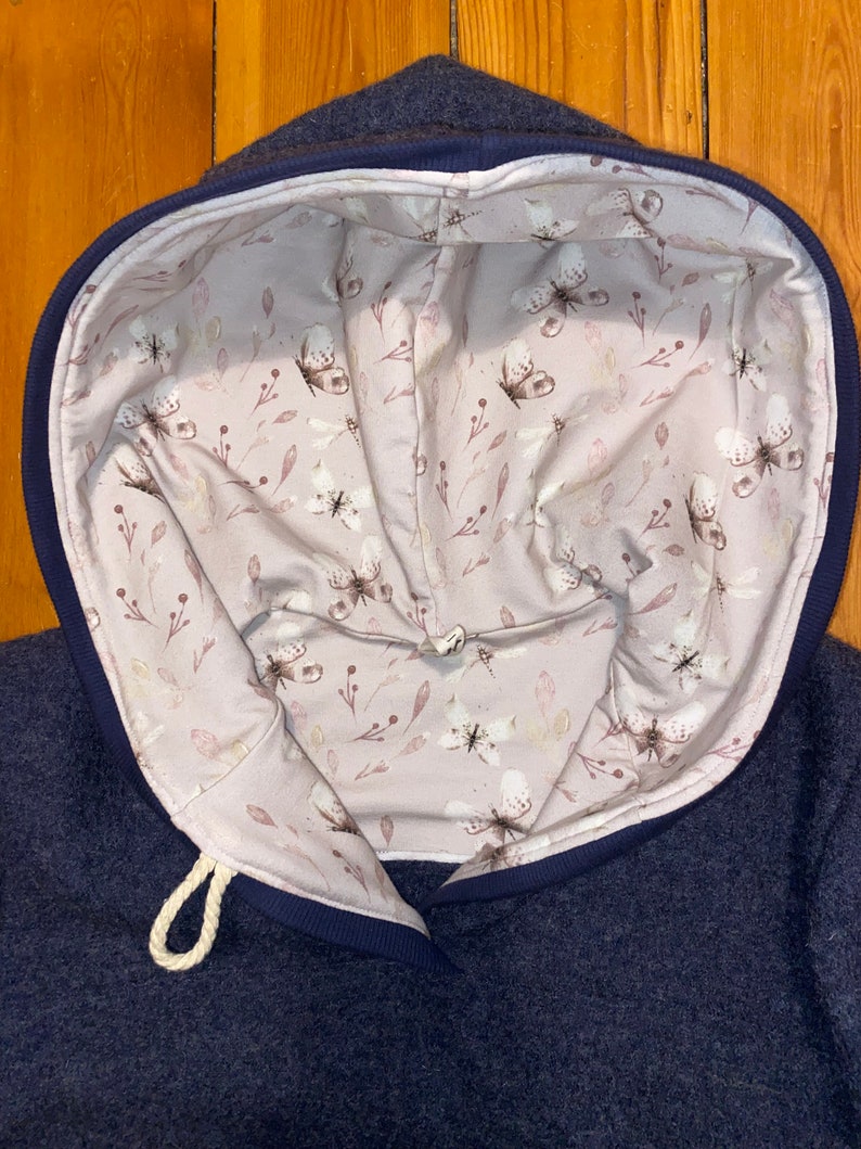 May include: A navy blue hoodie with a white drawstring and a pink floral lining featuring a butterfly pattern.