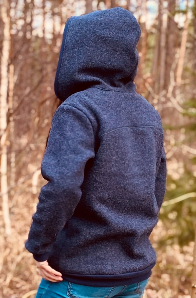 May include: A dark blue hooded sweatshirt with a soft, fuzzy texture. The sweatshirt has a zipper closure and a relaxed fit.