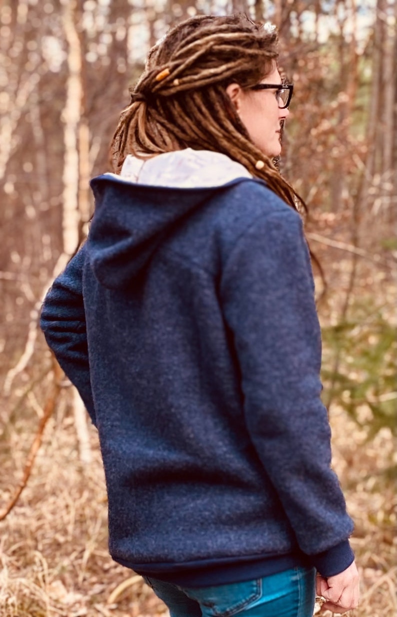 May include: A navy blue hooded sweatshirt with a zipper closure. The sweatshirt has a soft, fuzzy texture and a relaxed fit.
