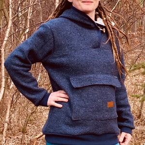 May include: A dark blue hooded sweatshirt with a large front pocket and a button closure at the neck. The sweatshirt has a textured fabric and a relaxed fit.