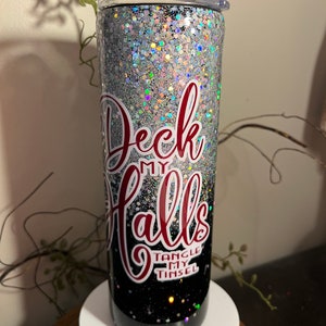 May include: A black and silver glitter tumbler with a red and white design that says "Deck My Halls" and "Tangle My Tinsel".