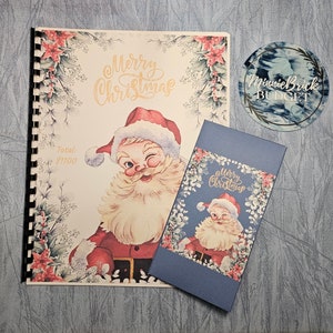 May include: A Christmas budget book with a vintage Santa Claus illustration on the cover. The book has a spiral binding and a blue cover with the text "Merry Christmas" and "Total: $1100".