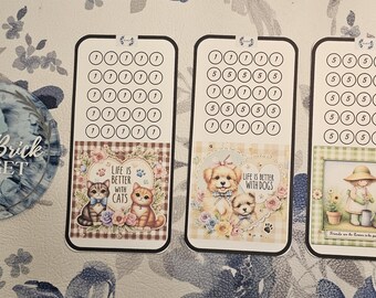 May include: Three decorative budget trackers with a floral design. One features cats with the text "Life is Better with Cats." Another shows puppies with the text "Life is Better with Dogs." The third depicts a girl gardening.