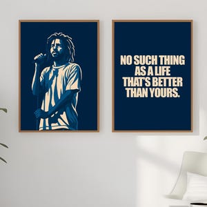 May include: Two framed art prints. One features a blue and white illustration of a person with dreadlocks holding a microphone. The other print has the text "NO SUCH THING AS A LIFE THAT'S BETTER THAN YOURS" in white on a blue background.