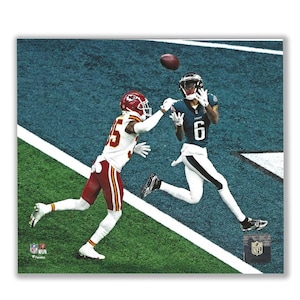 May include: A football player in a blue and white uniform jumps to catch a football thrown by a player in a red and white uniform. The player in the blue and white uniform is wearing a helmet and has the number 6 on his jersey. The player in the red and white uniform is wearing a helmet and has the number 35 on his jersey.