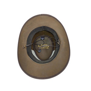 K&ouml;nnte beinhalten: Brauner Leder-Cowboyhut mit schwarzem Band und braunem Lederriemen. Der Hut hat ein Etikett mit der Aufschrift "LESA COLLECTION" im Inneren.