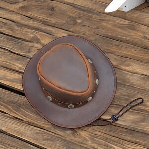 May include: A brown leather cowboy hat with a wide brim and a decorative band of silver studs.