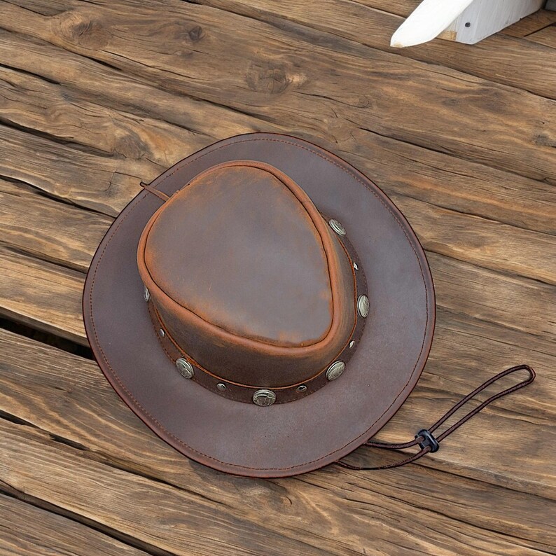 May include: A brown leather cowboy hat with a wide brim and a decorative band of silver studs.