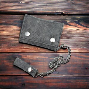May include: A grey leather wallet with a chain attached. The wallet has two silver snaps and the chain is made of silver metal.
