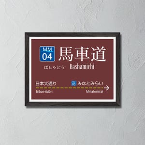 Può includere: Un cartello marrone e bianco con lettere nere e una cornice nera. Il cartello recita "MM 04 馬車道 Bashamichi" e indica le direzioni per "Nihon-ōdōri" e "Minatomirai".