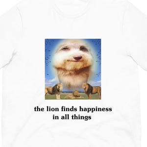 May include: White t-shirt featuring a humorous graphic. The graphic includes a smiling dog's face with a halo, three lions, and the text "the lion finds happiness in all things".