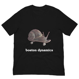 May include: Black t-shirt featuring a snail riding a skateboard. The snail has a brown shell and is on a gray skateboard. The words "boston dynamics" are printed in white below the graphic.