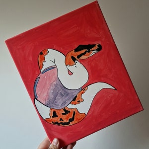 Può includere: Una tela dipinta a mano con un serpente bianco e arancione con un design a spirale viola e rosa. Il serpente è arrotolato su uno sfondo rosso.