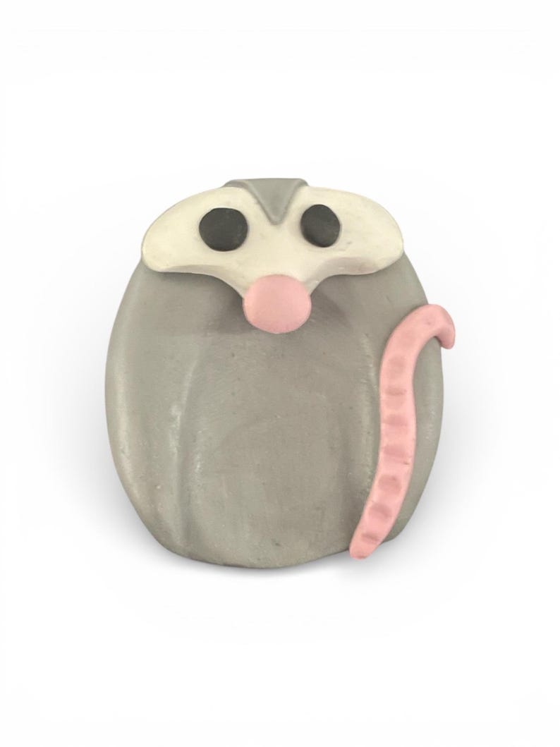 Pu&ograve; includere: Figurina di opossum grigia fatta a mano con viso bianco, occhi neri e naso e coda rosa. L'opossum ha un design stravagante, simile a un cartone animato, ideale per gli amanti degli animali.