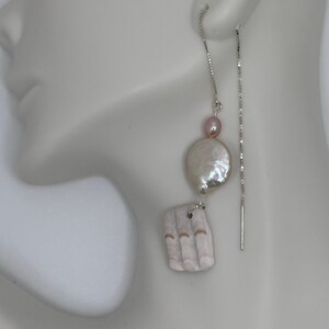 May include: A pair of silver chain earrings with a white shell and a pink pearl charm.