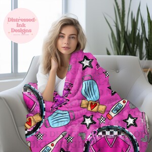 Puede incluir: Una manta de forro polar rosa con gráficos de temática médica, que incluyen un termómetro, una mascarilla y estrellas. La manta tiene un patrón repetitivo y el texto "98.6". Impresión digital.