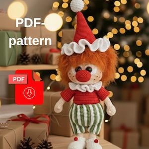 Könnte beinhalten: Handgefertigte gehäkelte Clownpuppe mit rotem Hut, Hemd und Nase sowie grün-weiß gestreiften Hosen. Die Puppe hat orangefarbene Haare und weiße Schuhe. Der Text "PDF-pattern" und ein PDF-Download-Symbol sind enthalten.