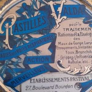 May include: A vintage tin container for Valda Pastilles, a French brand of cough drops. The tin is gold with blue and white lettering that reads "Pastilles Valda" and "Traitement Rationnel & Energique des Maladies des Voies Respiratoires." The tin also features a blue and white illustration of a stylized plant.