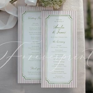 Könnte beinhalten: Hochzeitsprogramme mit rosa und weißen Streifen, mit den Namen "Amelia & James" und Hochzeitsdetails. Ein Strauß weißer Blumen mit weißem Band liegt auf den Programmen auf einer cremefarbenen Oberfläche.