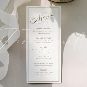 May include: A rectangular menu card with a green border and elegant script. The menu lists a multi-course meal, including a salad, soup, entr&eacute;e, and dessert. The card is on a light-colored surface with a white ribbon and floral arrangement.