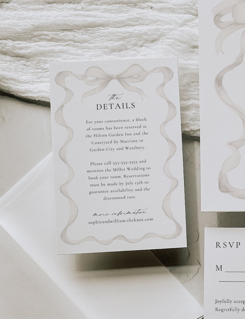 May include: A white wedding invitation card with a watercolor illustration of a bow. The text on the card reads "The Details" and includes information about hotel room reservations for the Miller Wedding. The card also includes the website "sophieandwilliam.theknot.com".