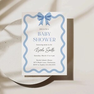 Peut inclure: Une invitation de f&ecirc;te pr&eacute;natale bleue et blanche avec un n&oelig;ud bleu en haut. L'invitation indique "Rejoignez-nous pour une f&ecirc;te pr&eacute;natale en l'honneur de la future maman Nicole Smith. Samedi 15 mars &agrave; 16h00. Maison de Rachel Adam, 2074 Maple Lane, Charleston. RSVP &agrave; Sophie 333.444.5555"