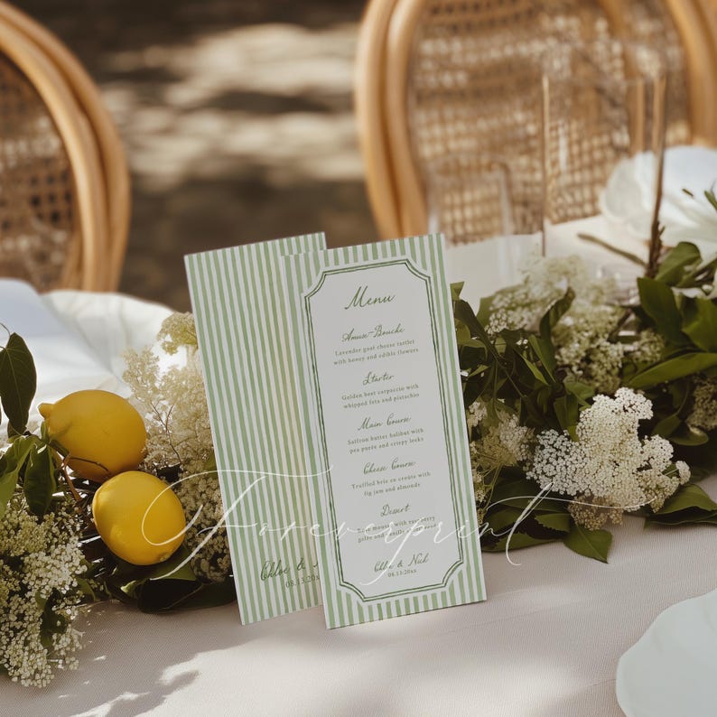 Op de afbeelding: Twee menukaarten met een groen en wit gestreept patroon, met een decoratieve rand en elegant schrift. De menukaarten worden gepresenteerd op een tafel met citroenen en witte bloemen. Het woord "Menu" staat bovenaan.