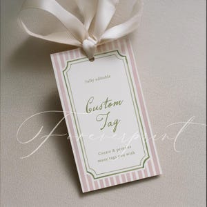 May include: A rectangular custom tag with a pink and white striped background and a green and white decorative border. The tag has the words "Custom Tag" in a cursive font and is tied with a cream-coloured ribbon.
