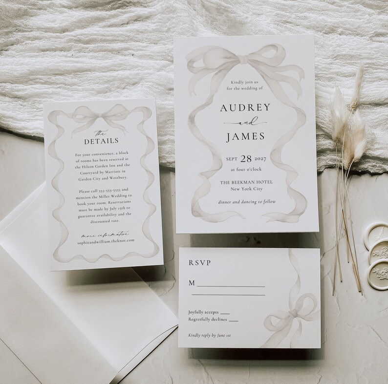 May include: Wedding invitation suite with a watercolor ribbon design. The invitation features the names Audrey and James, the date September 28, 2027, and the location The Beekman Hotel, New York City. The RSVP card includes a space for guests to indicate their attendance.