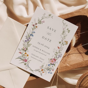 K&ouml;nnte beinhalten: Save-the-Date-Karte mit einem floralen Kranzdesign. Die Karte ist wei&szlig; mit schwarzem Text, der "Save the Date", "29.06.2024", "Sophie & William", "are getting married", "Tuscany, Italy" und "invitations to follow" lautet.