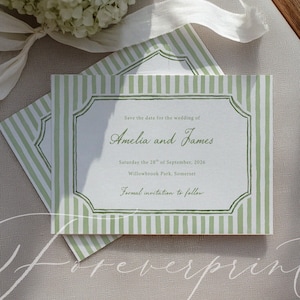 May include: A pair of wedding save-the-date cards with a green and white striped pattern. The cards display the names "Amelia and James" and wedding details. The rectangular cards have a decorative border and are stacked on top of each other.