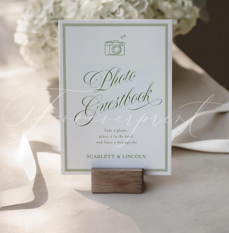 May include: A white Photo Guestbook sign with a green border and text. The sign features a camera icon and the words "Photo Guestbook". It includes the text "Take a photo, place it in the book and leave a message for Scarlett & Lincoln."