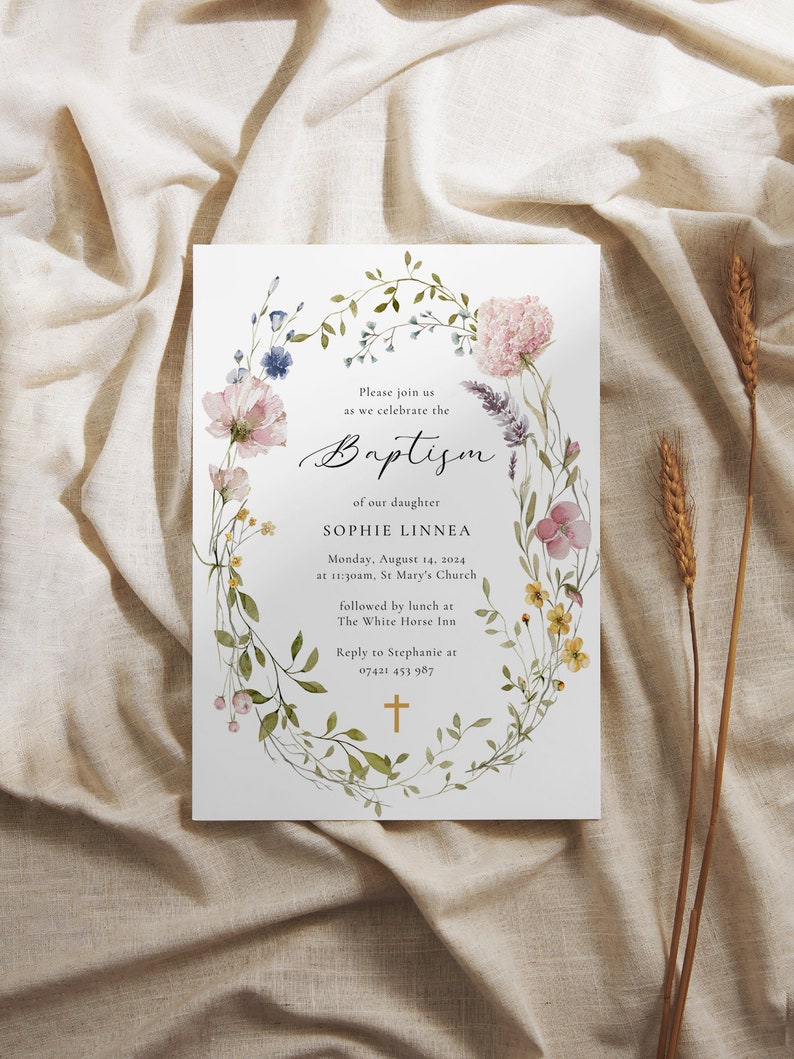 Peut inclure: Une couronne florale avec des fleurs aquarelle dans des tons de rose, bleu et jaune entoure le texte "Veuillez vous joindre &agrave; nous pour c&eacute;l&eacute;brer le bapt&ecirc;me de notre fille Sophie Linnea Lundi 14 ao&ucirc;t 2024 &agrave; 11h30, &Eacute;glise St Mary suivi d'un d&eacute;jeuner au White Horse Inn R&eacute;pondre &agrave; St&eacute;phanie au 07421 453 987". Une croix dor&eacute;e se trouve au bas de la couronne.