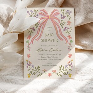 Op de afbeelding: Een bloemige babyshower-uitnodiging met een roze strik en de tekst "Sluit je aan bij ons voor een babyshower ter ere van de aanstaande moeder Blaise Jackson. Zaterdag 15 februari om 16:00 uur Rachel Adam's House 2074 Maple Lane, Charleston rsvp naar sophielu@gmail.com"