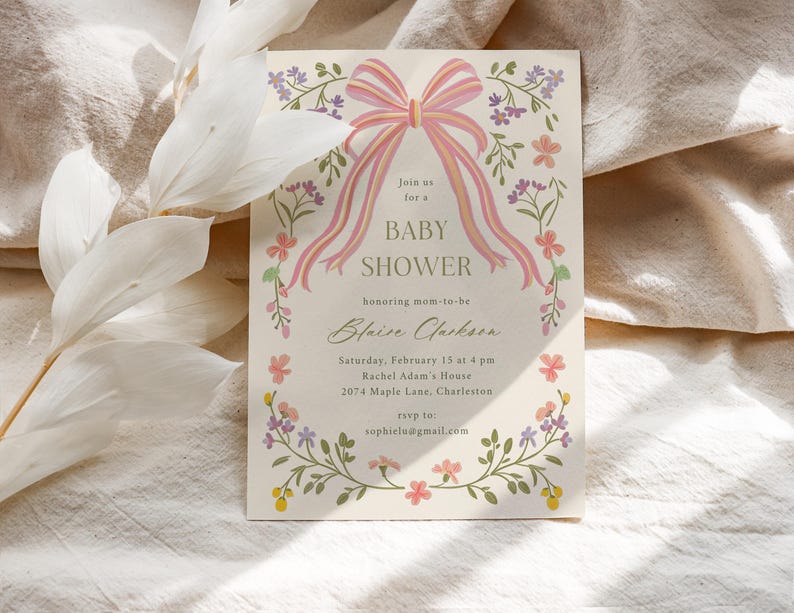 Op de afbeelding: Een bloemige babyshower-uitnodiging met een roze strik en de tekst "Sluit je aan bij ons voor een babyshower ter ere van de aanstaande moeder Blaise Jackson. Zaterdag 15 februari om 16:00 uur Rachel Adam's House 2074 Maple Lane, Charleston rsvp naar sophielu@gmail.com"