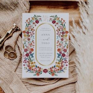 May include: A white wedding invitation with a gold border and floral design. The invitation reads "Kindly join us for the wedding of Anna and Theo, Saturday, July 14, 2 o'clock in the afternoon, The Ritz Carlton, 3300 SW 27th Avenue, Miami, FL 33155, Reception to follow."